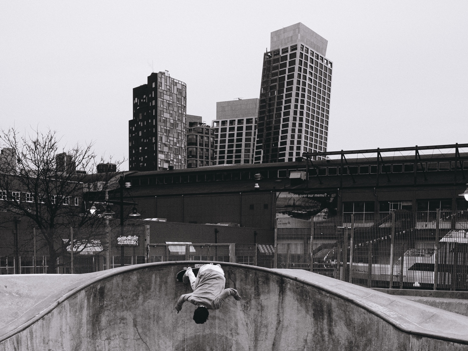 Skateboarder inverted above an urban bowl